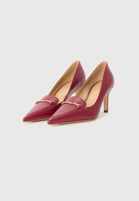 Décolleté in pelle bordeaux con tacco alto e punta affusolata, caratterizzate da un dettaglio decorativo in catena dorata sulla parte anteriore e un tacco sottile.