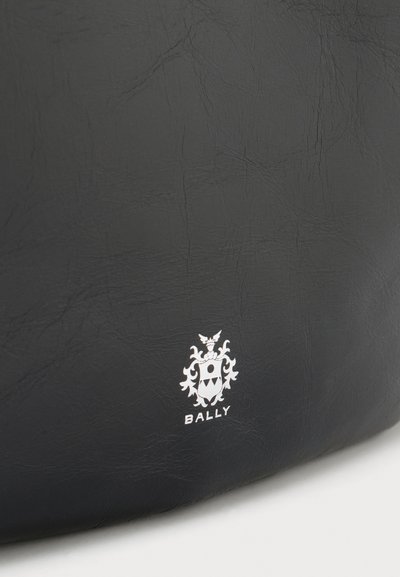 Melnas ādas soma ar maigu teksturētu virsmu un baltu Bally logotipu ar ģerboni apakšā.