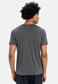 Grijze korte mouwen t-shirt met een ronde hals, zachte textuur en rechte zoom; achterstevoren gedragen, waardoor een eenvoudig ontwerp en minimale details zichtbaar zijn.
