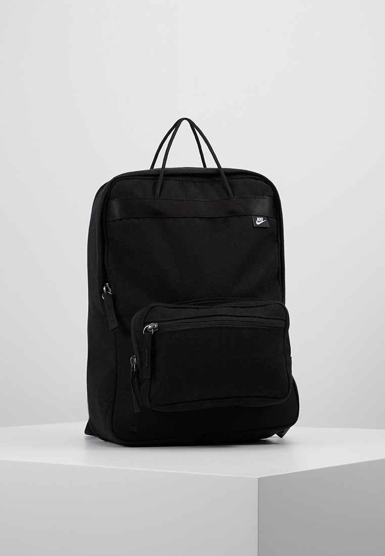 Sac à dos rectangulaire noir avec poche avant zippée, deux poignées supérieures et petit logo Nike blanc dans le coin supérieur droit.