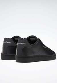 Black sports shoes with a smooth leather and suede finish. Low-top design, rubber sole, and embossed branding on the heel.