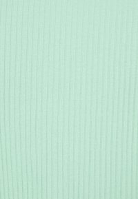 Texture de tissu en maille côtelée vert clair avec des lignes verticales.