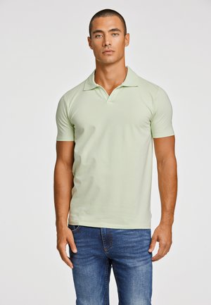 Hellgrünes Poloshirt aus glattem Stoff, mit klassischem Kragen und kurzen Ärmeln, kombiniert mit blauen Denim-Jeans.