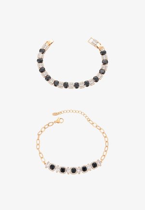 Dwie złote bransoletki, jedna z naprzemiennie ułożonymi owalnymi czarnymi i kwadratowymi białymi kamieniami, druga z czarnymi kamieniami i przezroczystymi okrągłymi akcentami.