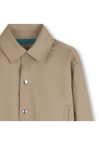 Ανοιχτό μπεζ πουκάμισο με γιακά, κουμπιά με πατιλέτα και υφή εσωτερικής φόδρας σε πετρόλ χρώμα. Δ ιαθέτει μία πλαϊνή τσέπη στο κάτω αριστερό μέρος.