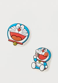 Twee rubberen badges met een blauwe cartoonkat met een witte buik en rode accenten. De ene toont een gezicht, terwijl de andere de kat aan het eten laat zien.