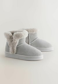 Grau Wildleder Stiefeletten mit einem flauschigen cremefarbenen Schaft, weißer Gummisohle, abgerundeten Zehen und glatter Oberfläche. Entworfen für Komfort und Wärme.