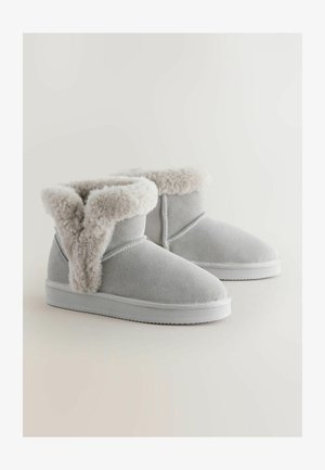 Szare zamszowe botki za kostkę z puszystym kremowym mankietem, białą gumową podeszwą, okrągłymi czubkami i gładką teksturą. Zaprojektowane z myślą o komforcie i cieple.