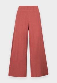 Pantalon large côtelé couleur terracotta avec taille haute, sans fermetures ni poches visibles, présenté à plat sur fond blanc.
