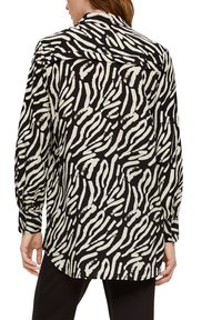 Schwarz- und cremefarbenes Hemd mit Knopfleiste, das ein Zebra-Streifen-Muster aufweist, lange Ärmel und einen klassischen Kragen hat. Leicht, entspannte Passform mit abgerundetem Saum.
