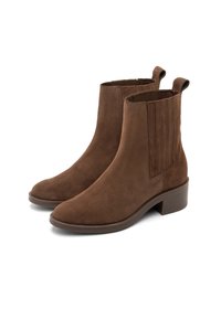 Botas de tobillo de ante marrón con puntera redondeada, paneles laterales elásticos y un tacón bajo en bloque. Presentan tiradores para facilitar su puesta.