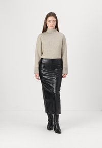 Béžový rolák s dlhými rukávmi v kombinácii s čiernou midi sukňou z faux kože. Modelka má na sebe čierne céčky vysoké nad kolená.