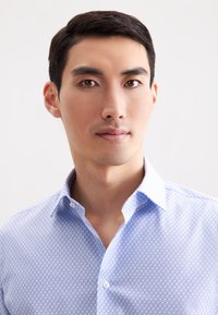 Lichtblauwe gedessineerde shirt met een klassieke kraag, knoopsluiting en een textuurstof met een diamantmotief.