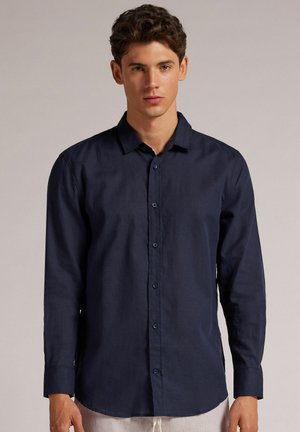 Dark blue, long-sleeve shirt made from a woven fabric with a collared neckline and button-down front. Smooth texture, minimal design, no visible patterns.