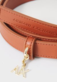 Brauner veganer Leder Gürtel mit geprägt "Armani Exchange" Logo, ausgestattet mit einem goldenen Metallanhänger mit "AX" Initialen und passenden Hardware-Details.