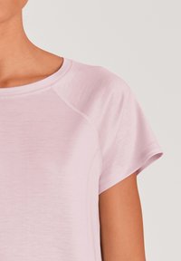 Light pink t-shirt with a round neckline and short raglan sleeves. The fabric appears soft and textured, featuring subtle stitching details.