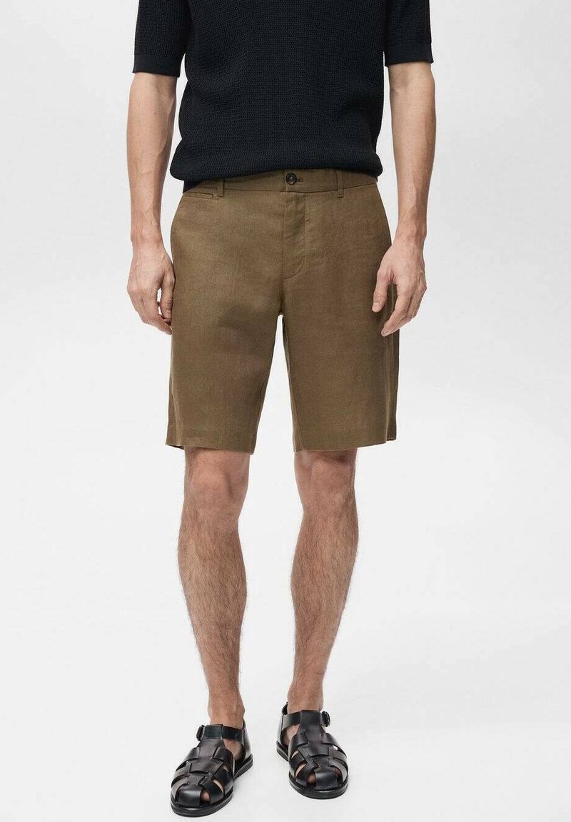 Shorts en lin marron avec une coupe droite, dotés d'une fermeture à bouton et de poches standard. Associés à des sandales tissées noires.