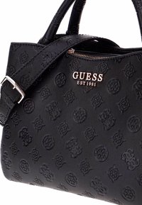 La borsa a tracolla in pelle nera presenta un motivo impresso, chiusura con zip e logo in tonalità argento "GUESS EST1981." Include due manici e una tracolla regolabile.