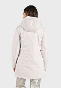 Lichtgrijze waterdichte jas met een capuchon, met een slank ontwerp, zachte textuur en zichtbare stiksels langs de naden.