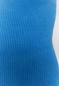 Blau gestreifter Stoff mit einer weichen Textur, der vertikale Linien zeigt und ein dezentes Muster bildet. Das Material wirkt leicht und flexibel.