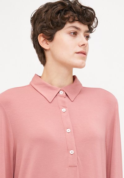 Ροζ μακρυμάνικη polo μπλούζα με γιακά και πέντε κουμπιά. Μαλακή, λείος υφή. Απλός σχεδιασμός χωρίς μοτίβα ή στολίδια.