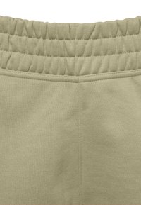 Light green sweatpants with a textured, elastic waistband. Soft material with visible stitching details and a smooth finish.