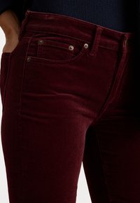 Burgunderfargede kordfløyelsjeans med en teksturert overflate, og to frontlommer, gullfarget hardware og en slank passform.