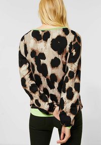 Halenka s dlouhým rukávem v leopardím vzoru, která má béžový, hnědý a černý motiv, s zeleným lemováním límce, z pohledu zezadu. Měkký materiál, volný střih.