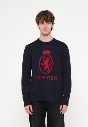 Camisola de malha azul-marinho com um emblema de leão vermelho e texto "HILFIGER", com decote redondo, punhos e bainha canelados.