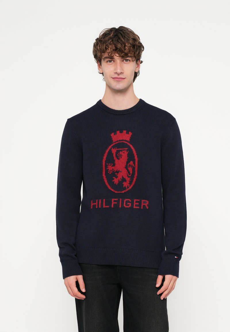 Maglione a maglia blu navy con emblema di leone rosso e testo "HILFIGER", con scollatura rotonda e polsini e orlo a coste.