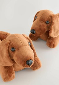 Kaisujõhiga täidetud dachshund, millel on pruun, pehme karv, suured mustad silmad ja must nina. Omab rippsüste kõrvu ja ümarat keha kuju.