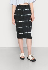 Černá midi sukně s bílými pruhy ve stylu tie-dye, s elastickým pasem na šňůrku. Nalezena s krémovými platformovými sandály. Hladká textura látky.