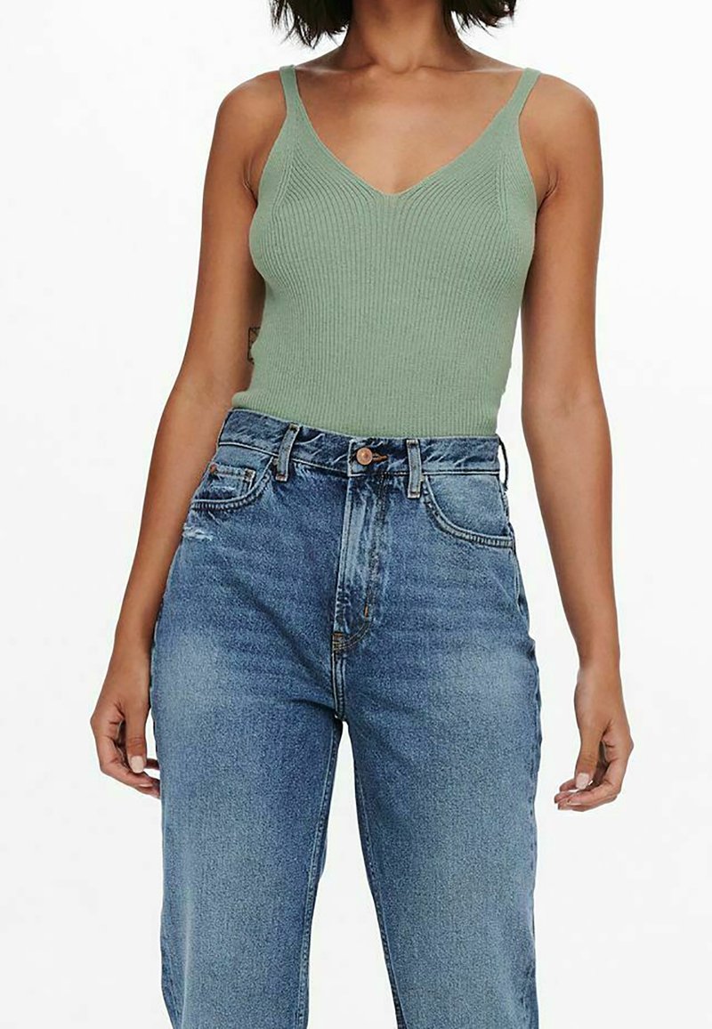 Débardeur côtelé vert olive avec un décolleté en V et des bretelles fines, associé à un jean en denim bleu clair taille haute avec une coupe décontractée.