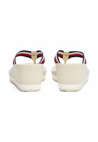 Sandali platform beige con cinturini a strisce nere, bianche e rosse. Il design presenta una finitura liscia e una suola leggermente texture.