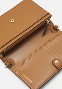 Braune Leder Geldbörse mit einem Reißverschlussfach und mehreren Kartenfächern. Ausgestattet mit goldfarbenen Beschlägen und geprägtem "MICHAEL KORS"-Logo.