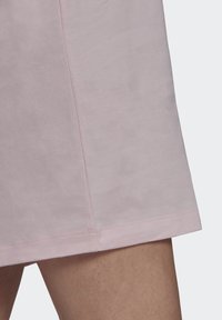 Světle růžové bavlněné šaty s jemnou texturou. Mají rovný lem a decentní boční švy pro jednoduchý design.