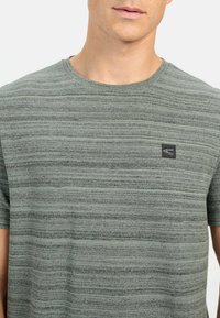 Grå kortærmet t-shirt med et struktureret horisontalt stribemønster og et lille sort logo på brystet. Blandingsstof af bomuld.
