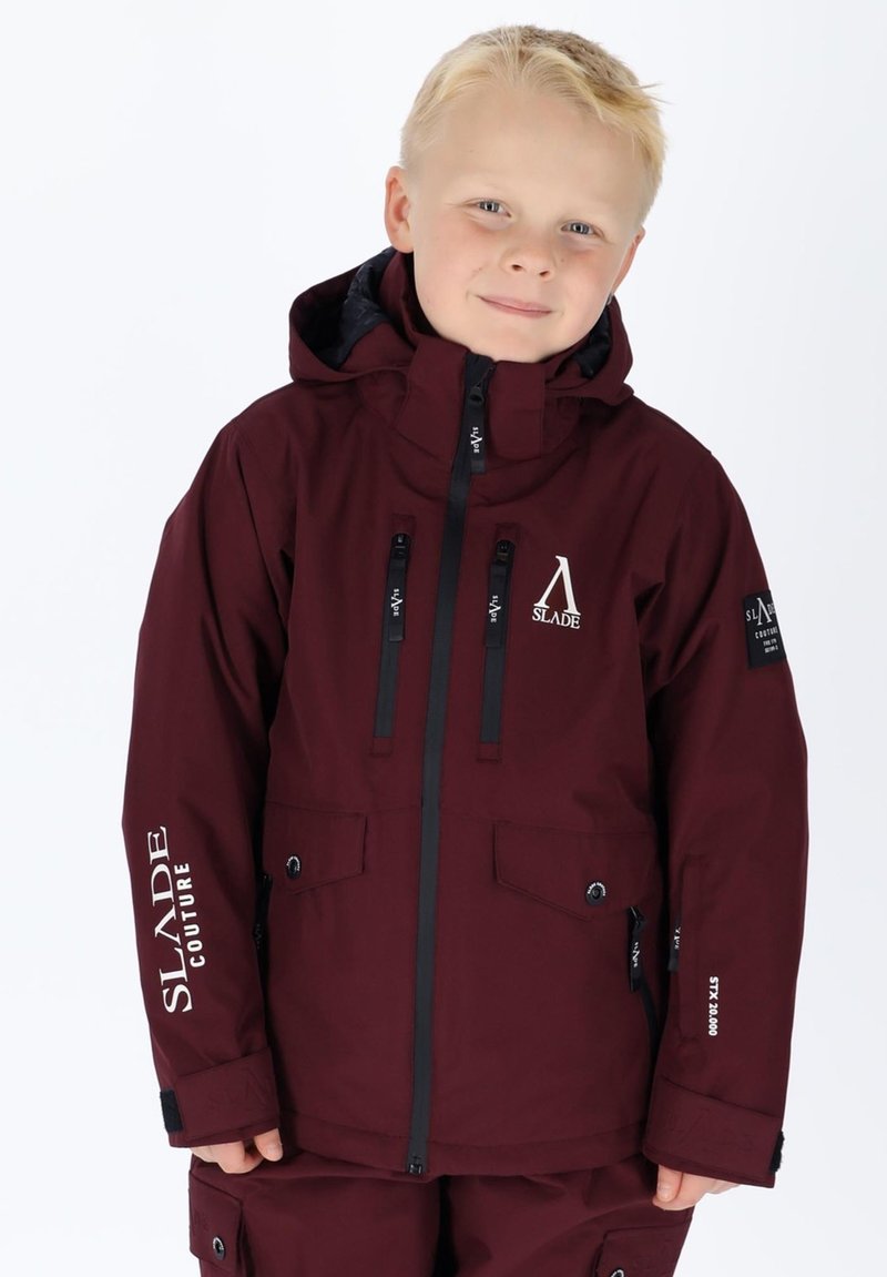 Giacca invernale bordeaux con cappuccio, cerniere nere e tasche. Presenta dettagli con logo e un tessuto impermeabile dalla consistenza liscia.