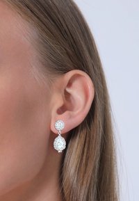 Boucles d'oreilles en argent avec une pierre ronde en haut et une pierre en forme de poire en dessous, toutes deux entourées d'accents scintillants.