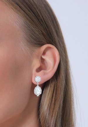 Silberne Tropf-Ohrringe mit einem runden Stein oben und einem tropfenförmigen Stein darunter, beide umgeben von glitzernden Akzenten.