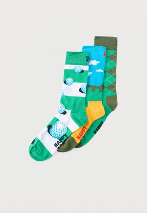 Trois paires de chaussettes colorées : une chaussette verte avec des balles de golf, une chaussette bleu clair avec des nuages, et une chaussette à motif losanges vert avec des accents jaunes.