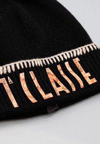 Cappellino a maglia nero con una fascia ricamata color crema e lettere in rilievo di colore beige con motivo a mappa.