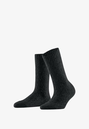 Ein Paar schwarze, knielange Wollsocken mit einem strukturierten Strickmuster, die aufrecht vor einem weißen Hintergrund stehen.