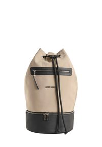 Bolsa de lona beige tipo cubo con base de cuero negro, bolsillo frontal con cremallera y cierre de cordón. Presenta una marca en la parte delantera.