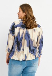 Blusa in crema, blu e navy con motivo astratto; presenta maniche a tre quarti, tessuto morbido e una vestibilità comoda.
