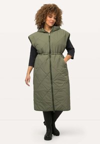 Olivegrön lätt vadderad väst med huva, med dragkedjeförslutning, elastisk midja och sidofickor. Lång, rak design.