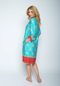 Jedwabny szlafrok w kolorze turkusowym z złotym wzorem, z czerwonym geometrycznym nadrukiem u dołu oraz dwiema bocznymi kieszeniami dla funkcjonalności.