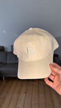 Beige corduroy baseball cap with a stitched white 'R' on the front, featuring six breathable eyelets and a slightly curved brim.
