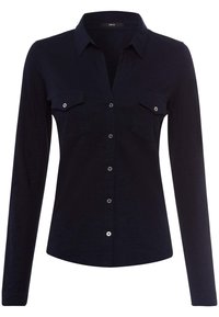 Chemise à manches longues de couleur bleu marine foncé avec un col, deux poches poitrine et une fermeture à boutons à l'avant ornée de boutons en argent brillant.