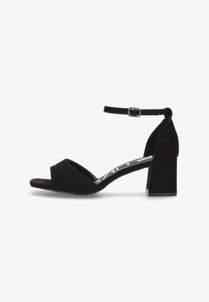 Sandalia de tacón alto de ante negro con punta abierta, tira al tobillo y tacón cuadrado. Textura suave y diseño sencillo.